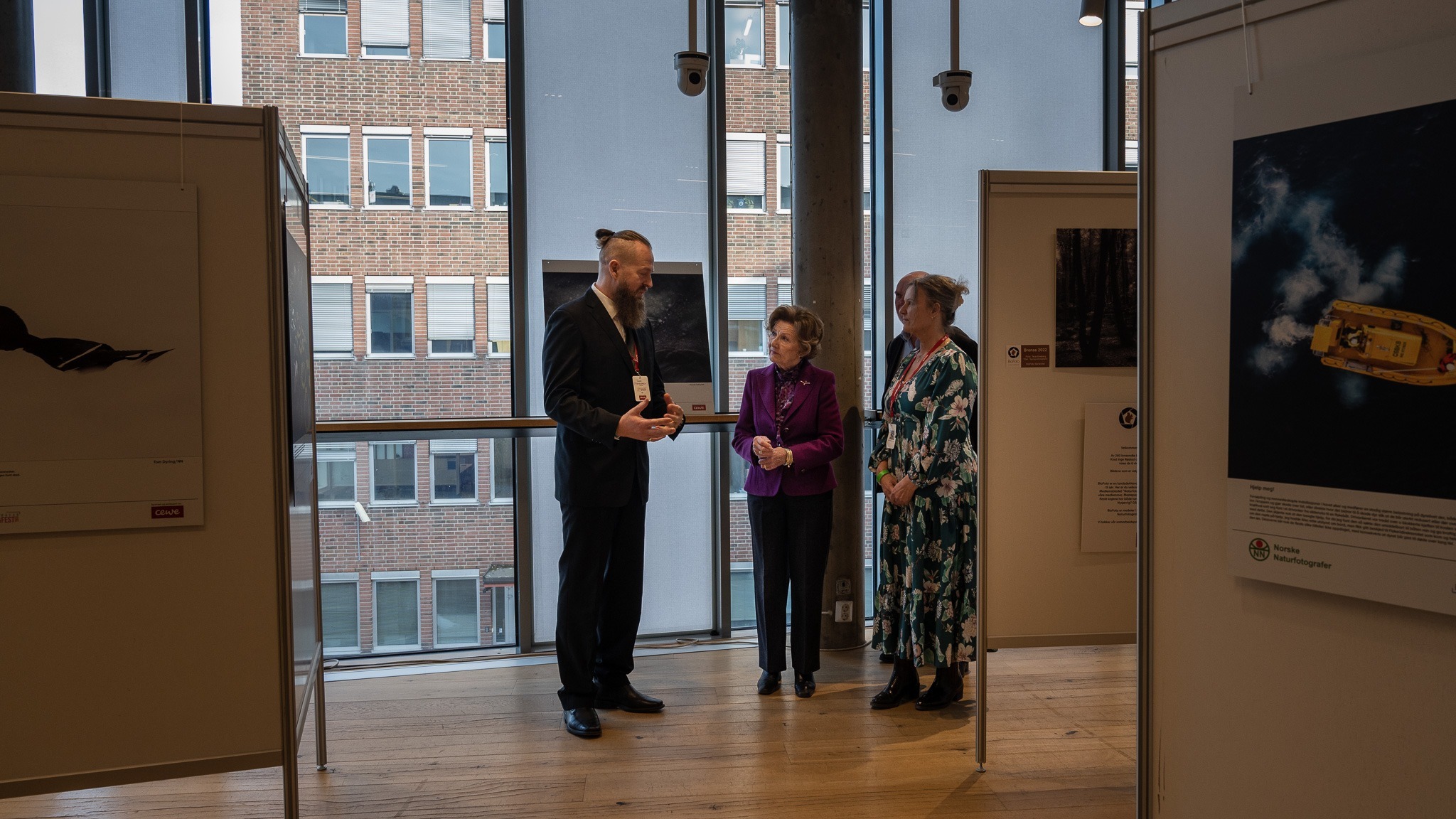 Roger Brendhagen og Heidi Mellingen viser Dronningen rundt på utstillingene til Norske Naturfotografer/NN og Biofoto. (Foto: Per Flakstad)
